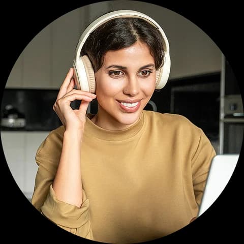 A woman wearing headphones and smiling while looking at a screen, representing a live tutoring session.